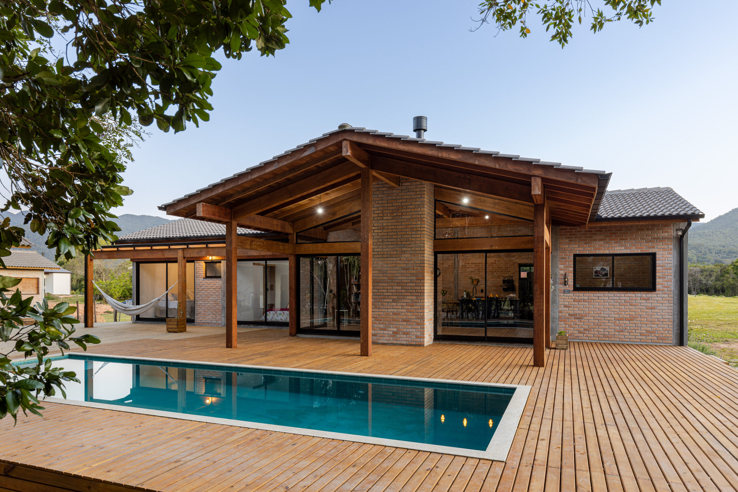 Casa Lar do Samba com piscina, deck de madeira e fachada em tijolo maciço com telhado aparente